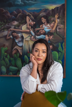 Cha Gutiérrez sitting in front of painting