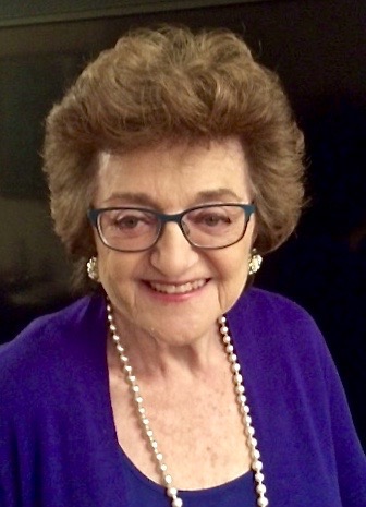A portrait of a woman wearing glasses and smiling at the camera.