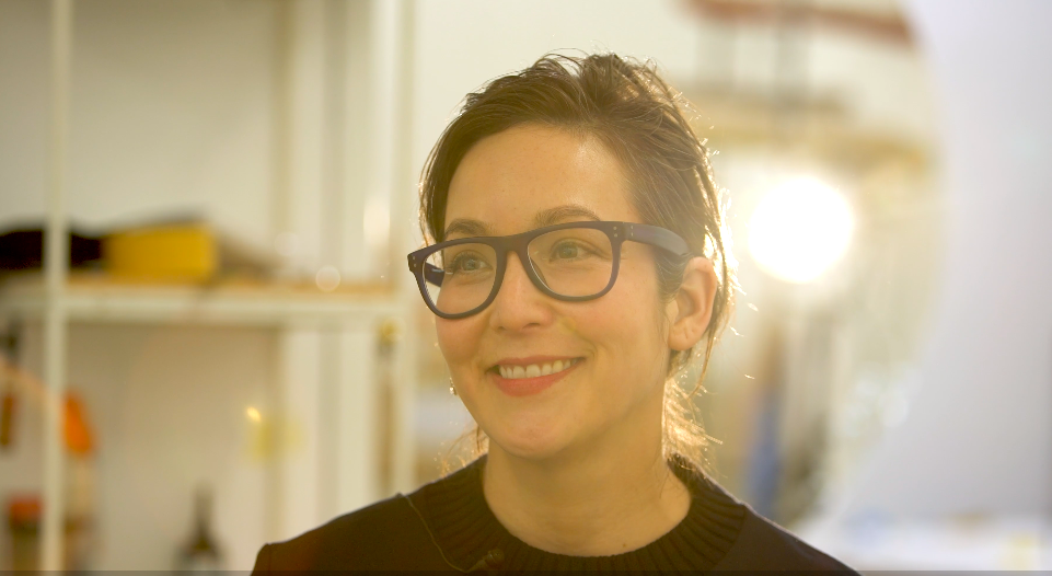 A woman surrounded by sunlight, smiling while looking to the right. 