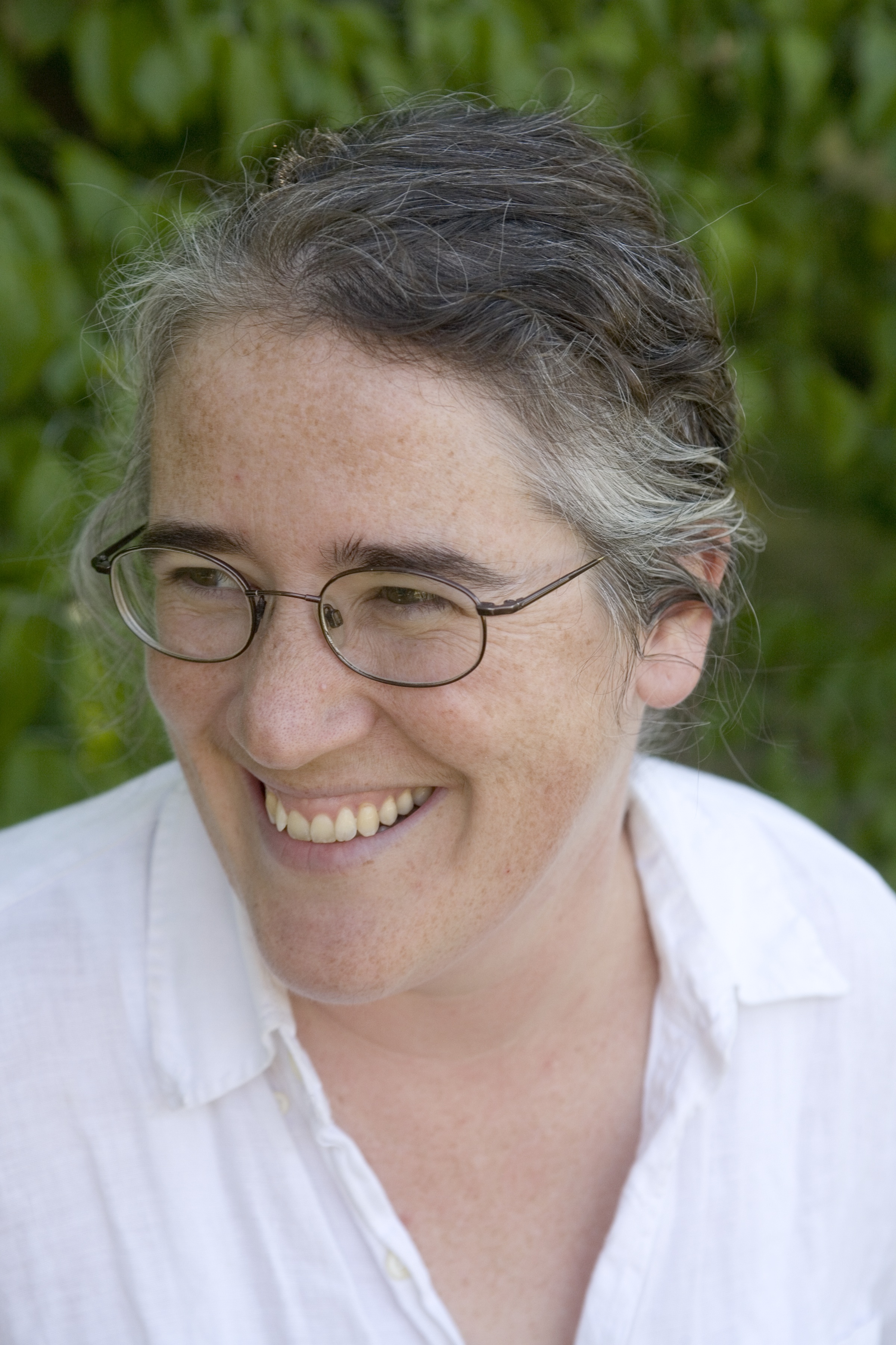 A woman wearing glasses and smiling as she looks to the right. 