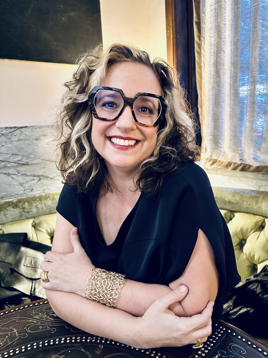 A woman wearing glasses and smiling at the camera